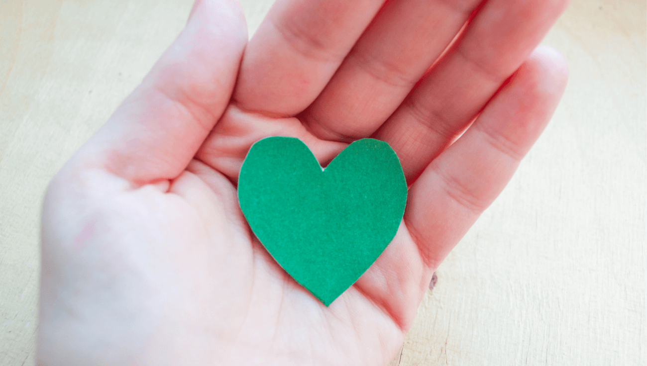 cœur en papier vert au creux d'une main